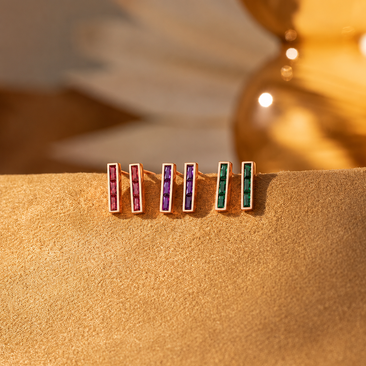 Set of four gemstone earrings on a beige surface with a blurred background